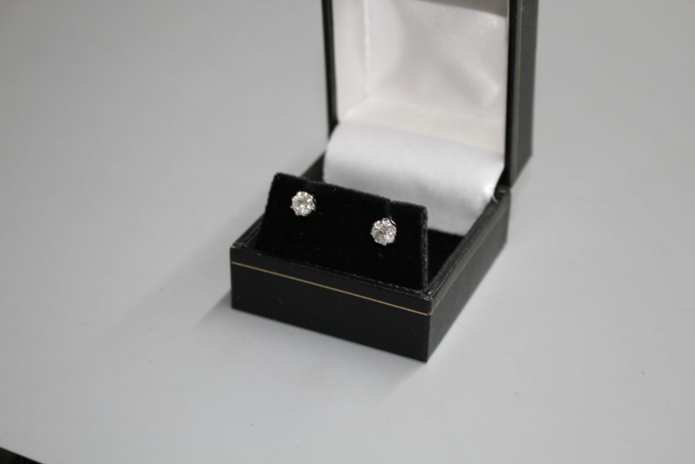 A pair of white metal and solitaire diamond ear studs,